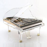 Transparent grand piano with clear acrylic body and gold accents, showcasing its unique modern design.