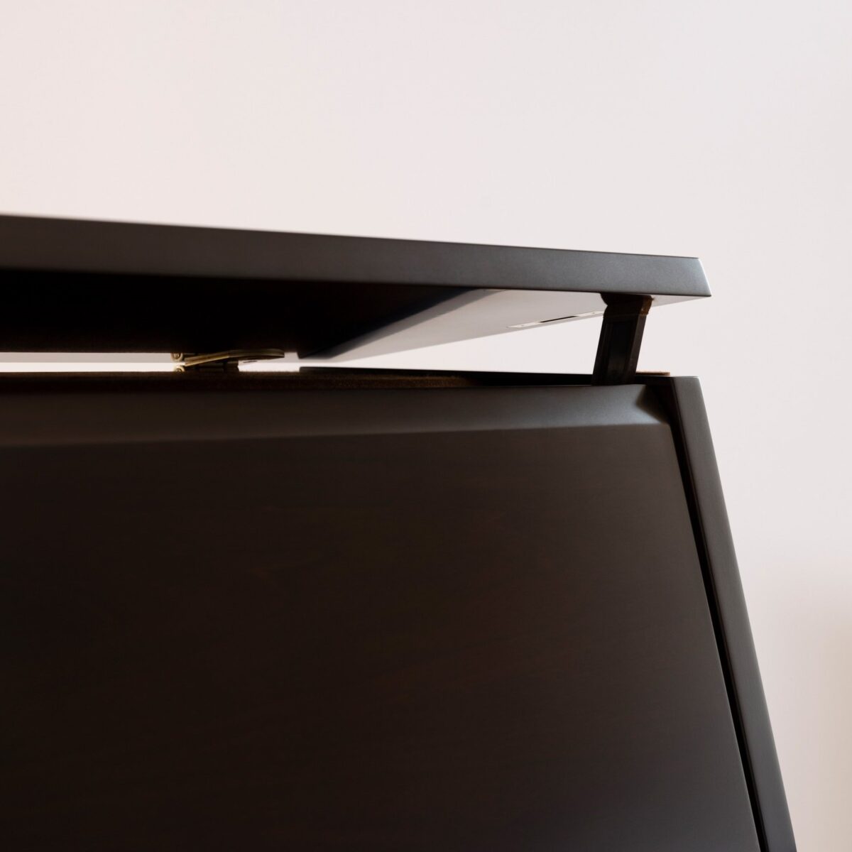 Close-up of a piano lid hinge showcasing sleek ebony finish from Classic Pianos Reno's premium upright collection.