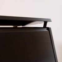 Close-up of a piano lid hinge showcasing sleek ebony finish from Classic Pianos Reno's premium upright collection.