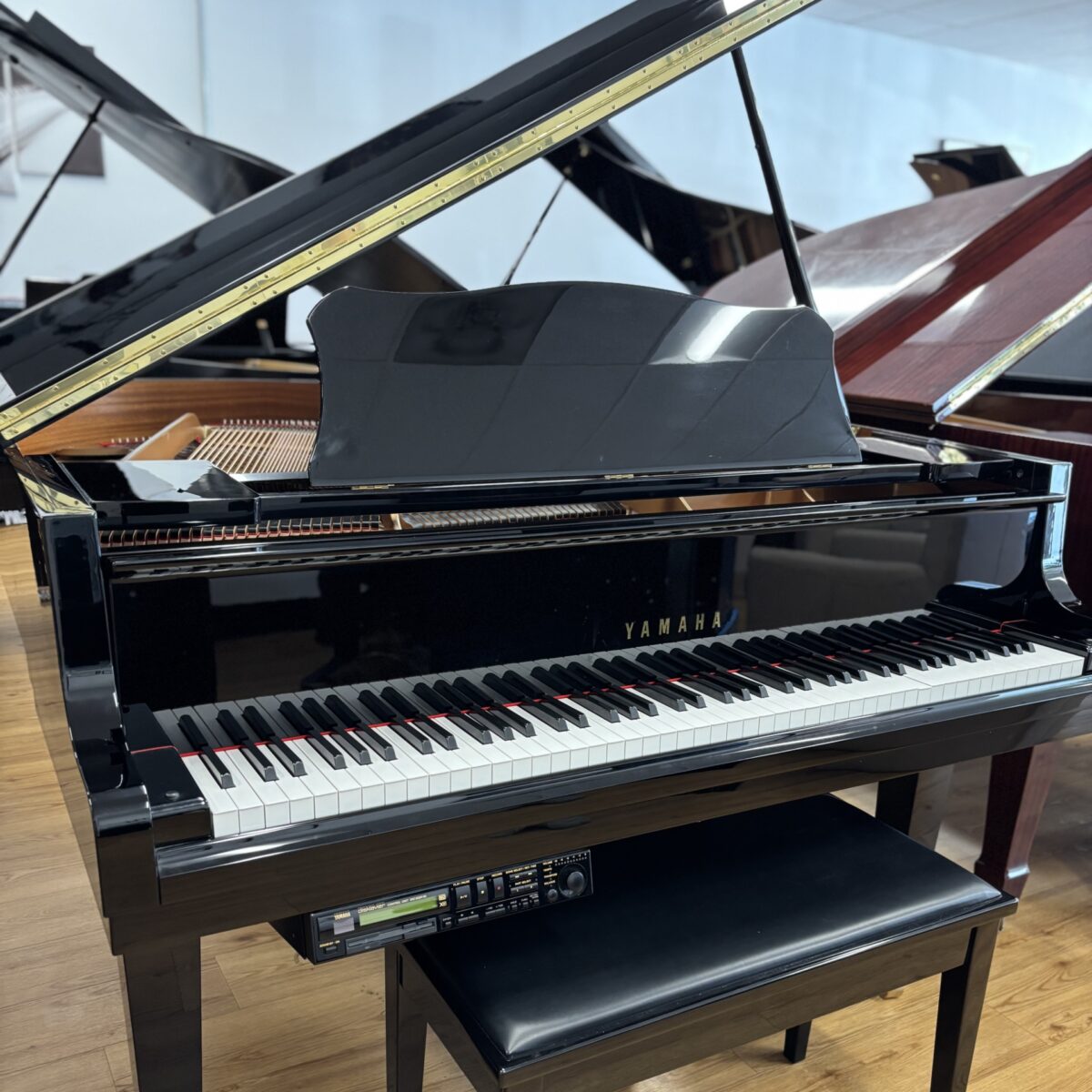 Alt text: Yamaha baby grand piano with a sleek black finish, featuring polished keys and integrated sound system for exceptional performance.