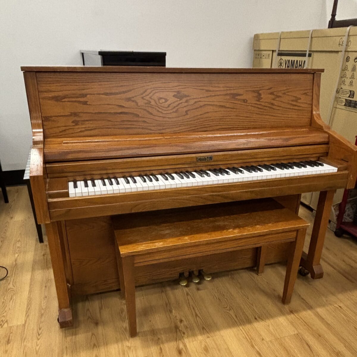 Vintage Yamaha upright piano featuring a rich oak finish and polished keys, perfect for any music enthusiast.