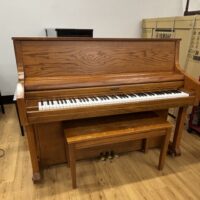 Vintage Yamaha upright piano featuring a rich oak finish and polished keys, perfect for any music enthusiast.
