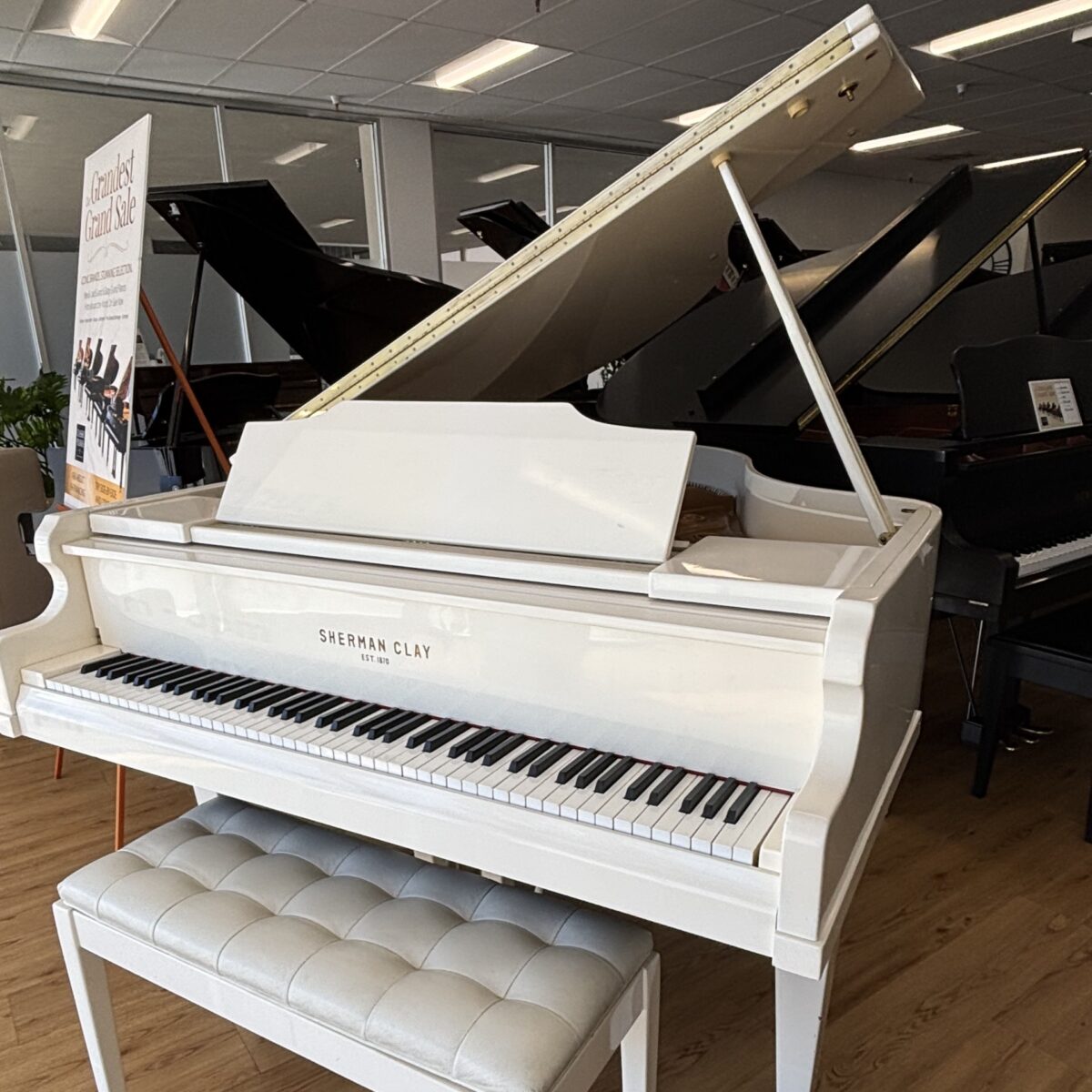 Alt text: Sherman Clay white grand piano with polished finish and plush bench, showcasing premium quality craftsmanship at Classic Pianos.