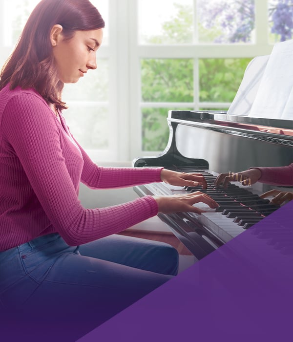 Young woman playing a polished grand piano, focusing on keys, showcasing passion for music at Classic Pianos Reno.