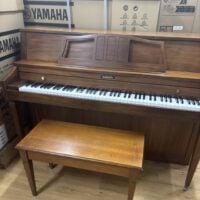 Baldwin upright piano with polished walnut finish and matching bench, ideal for home or studio use. Elegant craftsmanship.