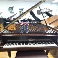 Alt text: Story & Clark grand piano featuring a polished mahogany finish and elegant carved music desk with patriotic ribbon.