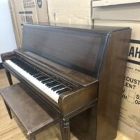 Vintage upright piano with polished mahogany finish, featuring 88 keys and decorative legs, perfect for home use.